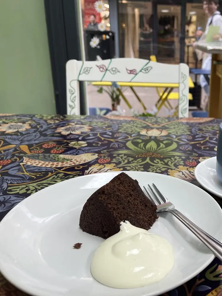 Chocolate cake with cream and a mug of coffee on a William Morris tablecloth