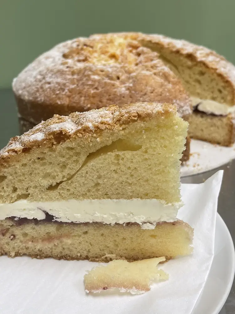 Victoria sponge cake with cream and jam, slice in front